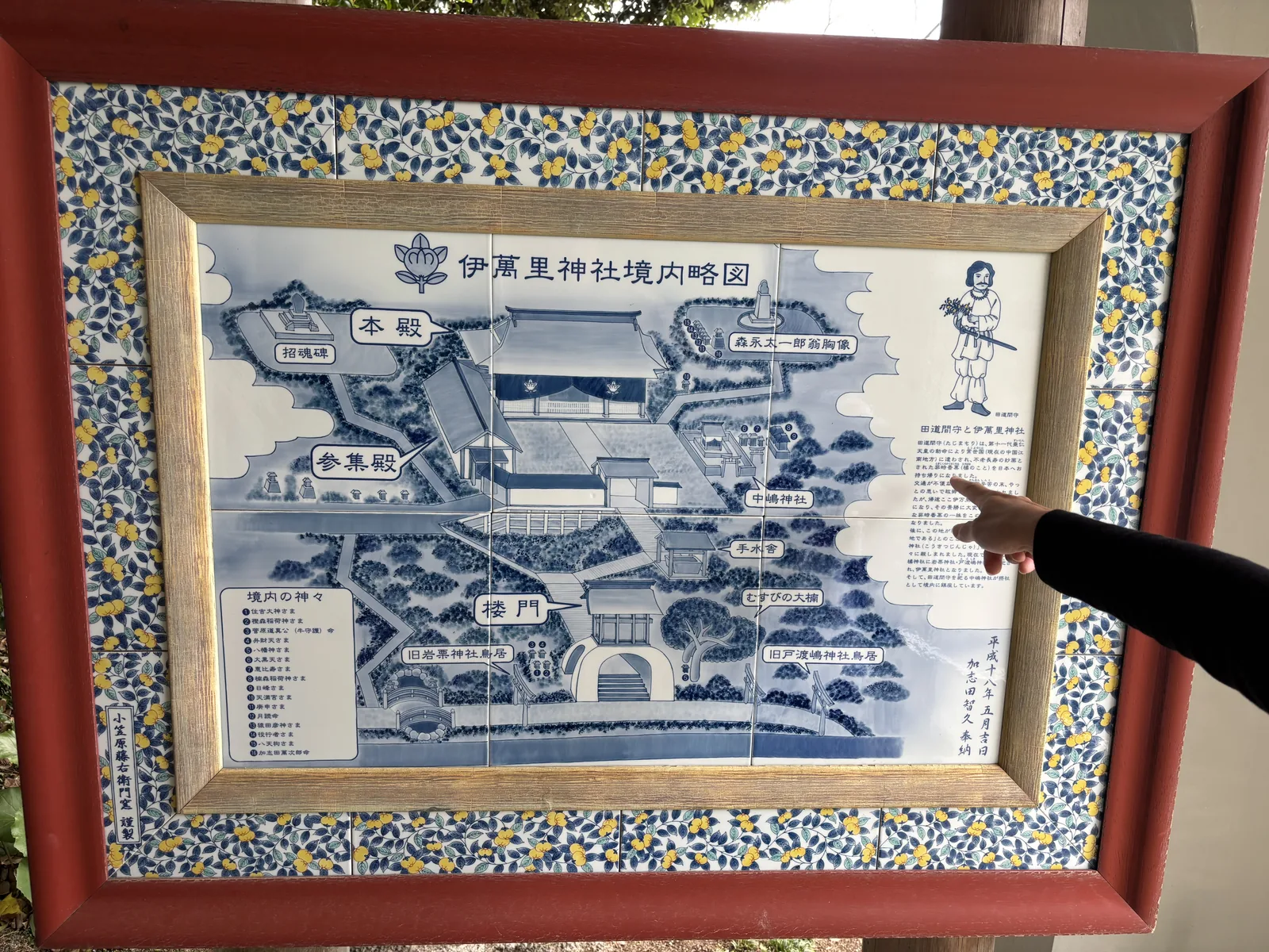 伊萬里神社的陶板製境內略圖，染付的藍白畫面上標著本殿、樓門、中嶋神社與各處節點，外框是黃綠色的果實紋樣