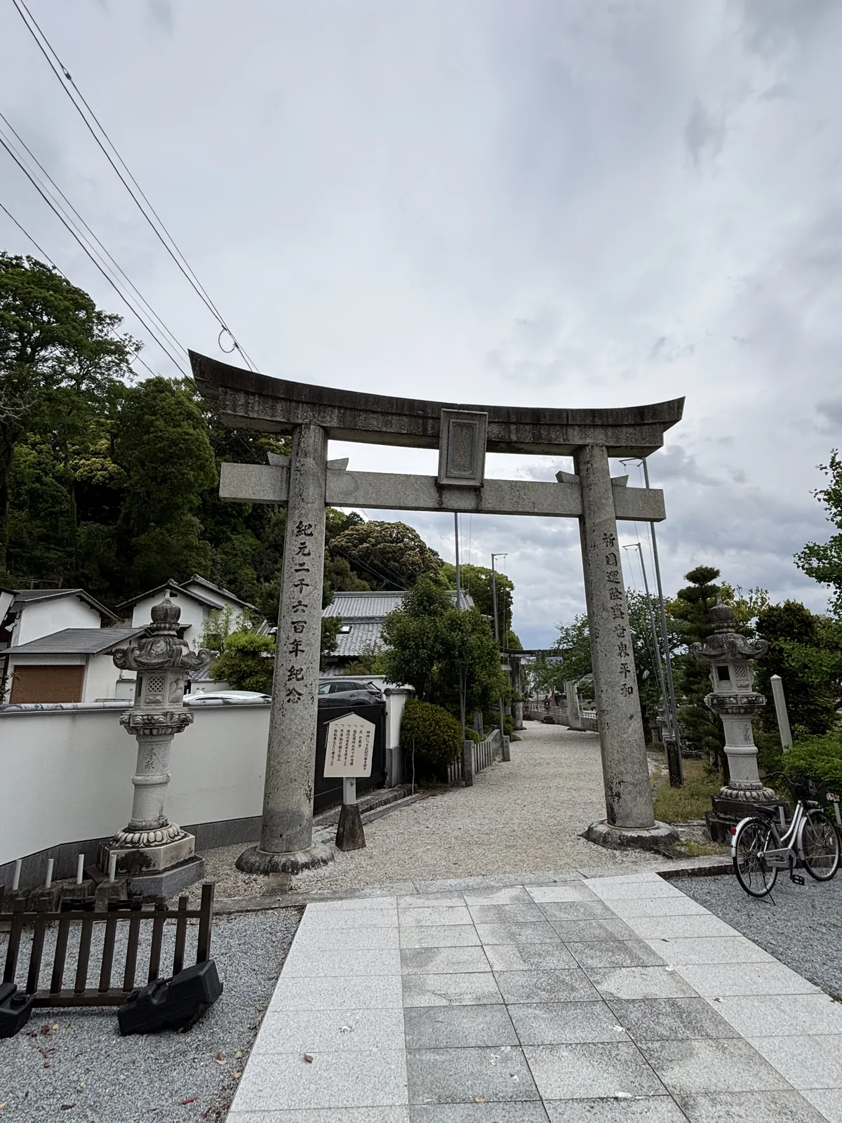 伊萬里神社的石造一之鳥居，左柱刻著紀元二千六百年紀念，兩側是石燈籠，後方是碎石參道