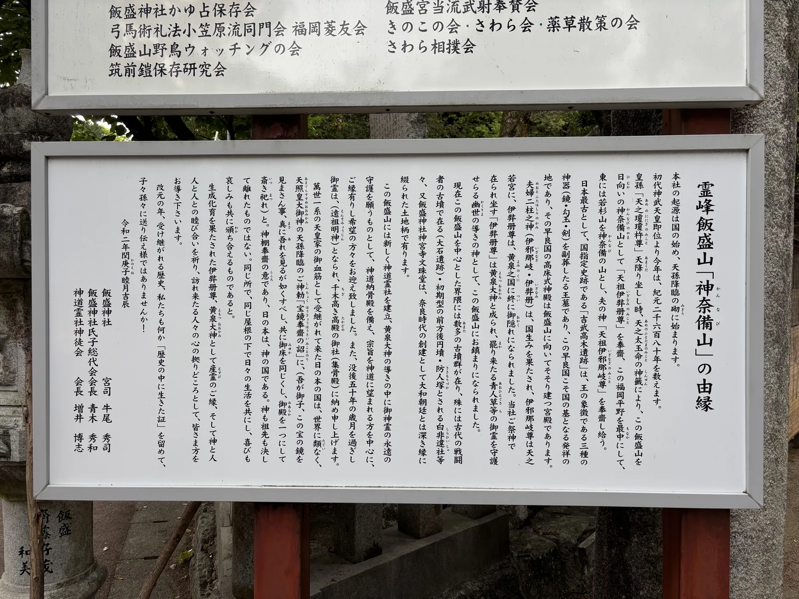 飯盛神社境內的「霊峰飯盛山『神奈備山』の由縁」說明板，密排直書文字，上方另有一塊列著各保存會名稱的板