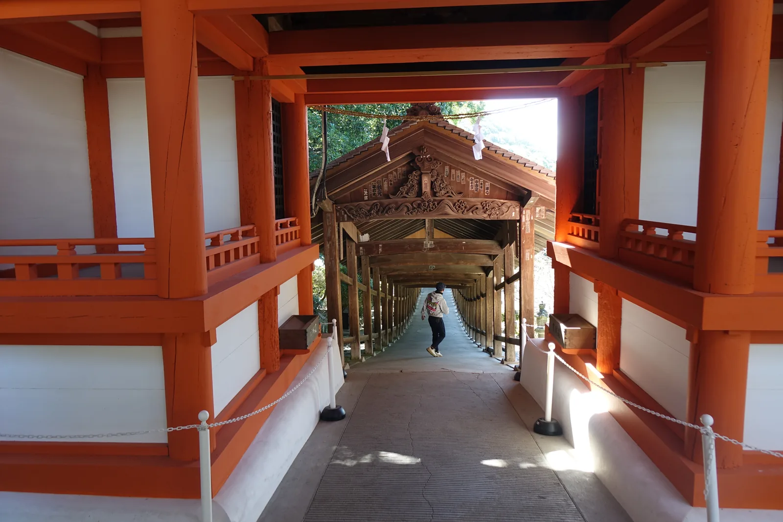 吉備津神社的南隨神門：朱塗的三間一戶八腳門橫跨在迴廊中途，門內可以看見蟇股的彫刻與繼續往南延伸的走廊