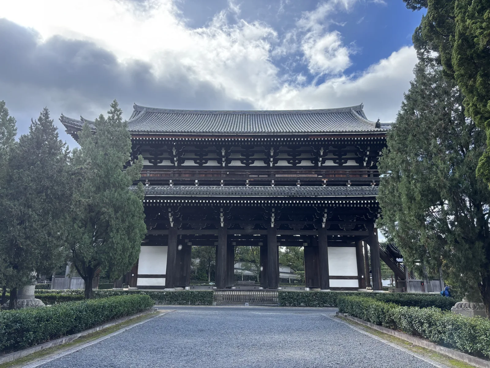東福寺三門正面：重層的木造大門，下層五間三戶，中央三個門洞兩側是白漆喰的袖壁，右端可以看見通往樓上的山廊，前方是碎石鋪成的空地