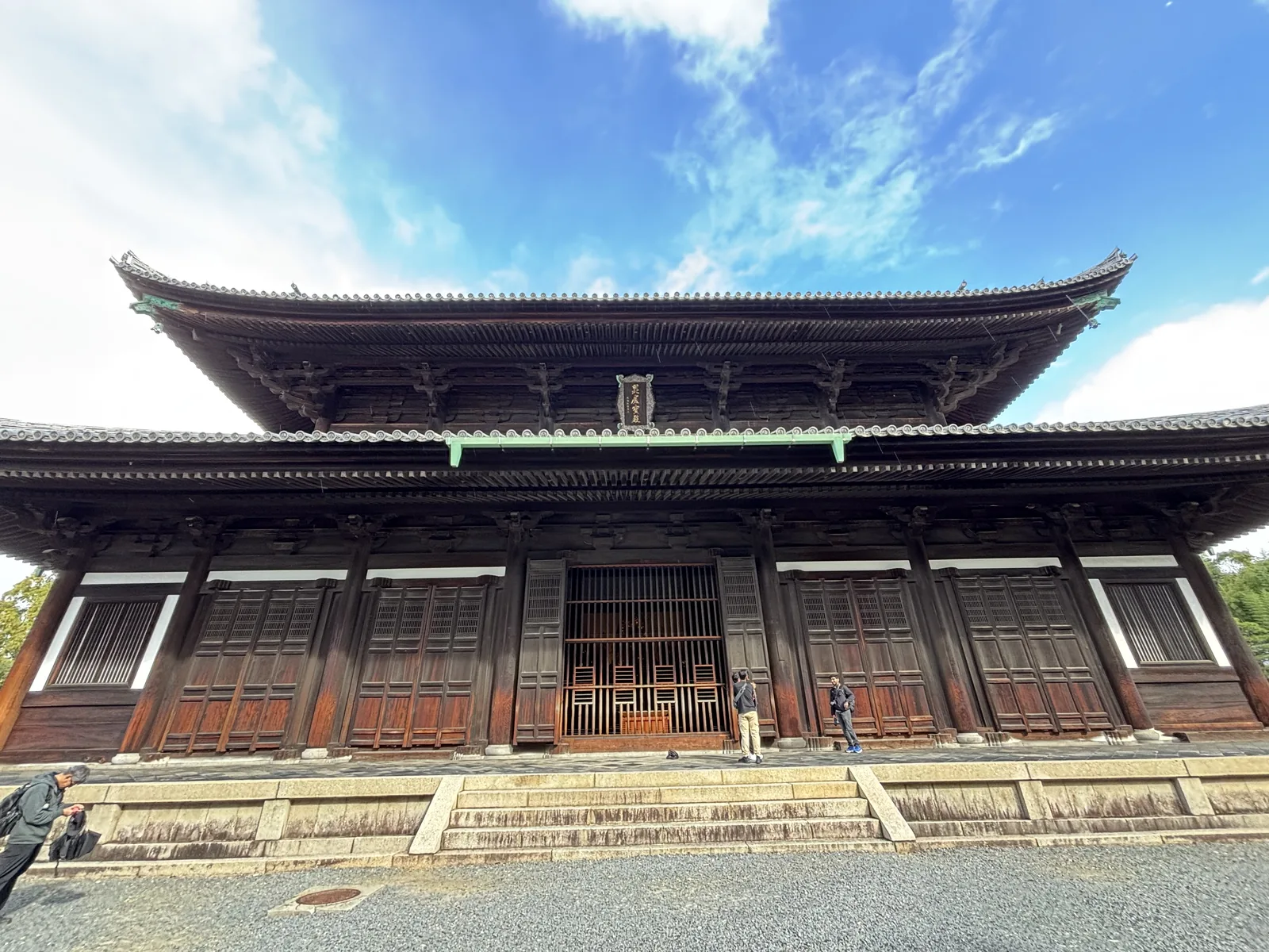 東福寺本堂（佛殿兼法堂）：重層入母屋造的大建築，上層屋簷下掛著扁額，下層一整排木格門，前方是石階與白砂