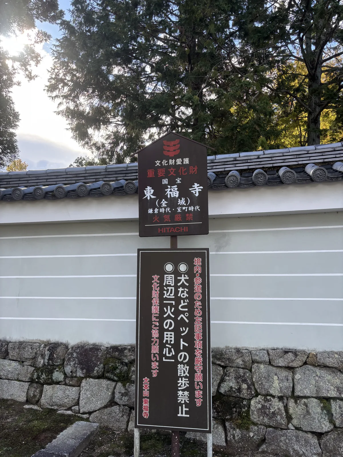 東福寺境內入口的文化財愛護木札，寫著「重要文化財　國寶　東福寺（全域）　鎌倉時代・室町時代　火氣嚴禁」，下方另一塊板是大本山東福寺署名的注意事項，背景是白色築地塀與石垣
