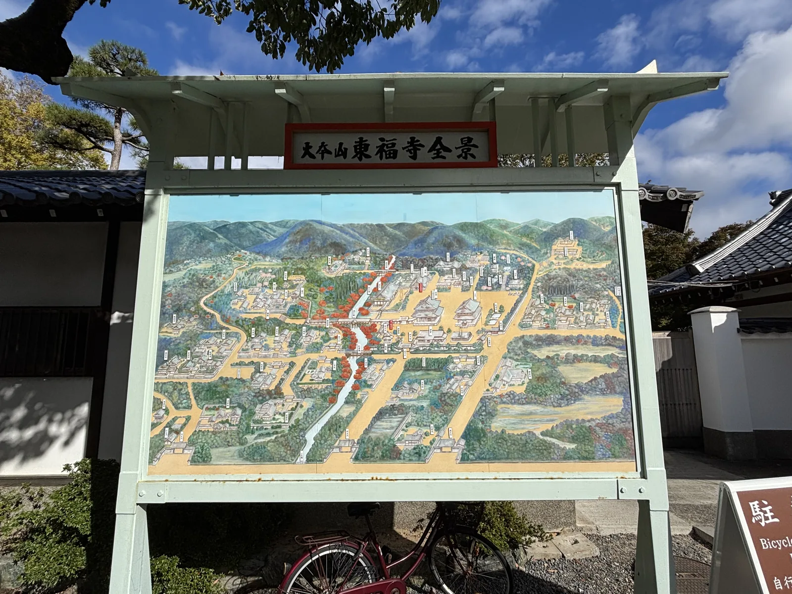 「大本山東福寺全景」的彩色鳥瞰圖看板，立在綠色的木框裡：畫面中央一條斜著穿過的綠帶就是洗玉澗，橋橫在它上面，四周散布著塔頭的屋頂