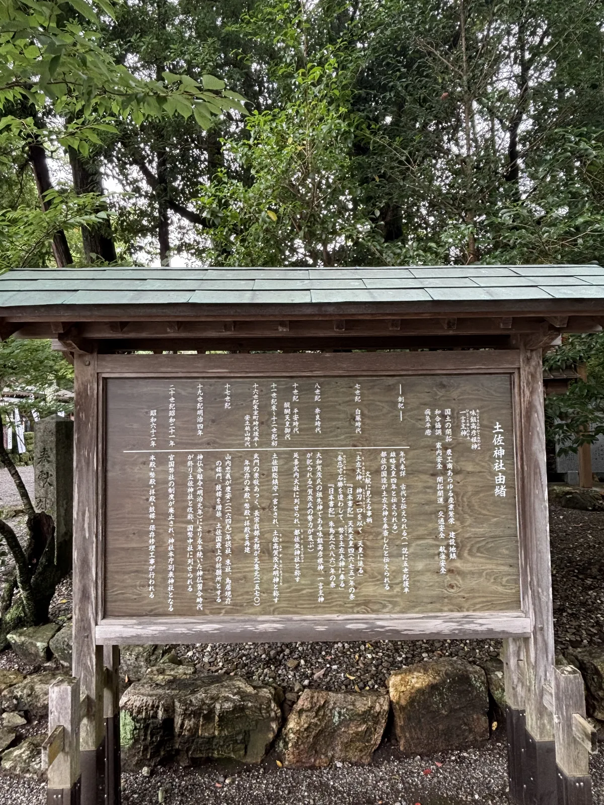 木造屋頂的大立牌。右欄記御祭神味鋤高彥根神・一言主神與九項御神德；左欄是世紀年表，第一行寫「創祀　年代未詳　古代と伝えられる（一説に五世紀後半　雄略天皇四年と伝えられる）」，第二行寫「都佐の国造が土左大神を奉斎したと伝えられる」。