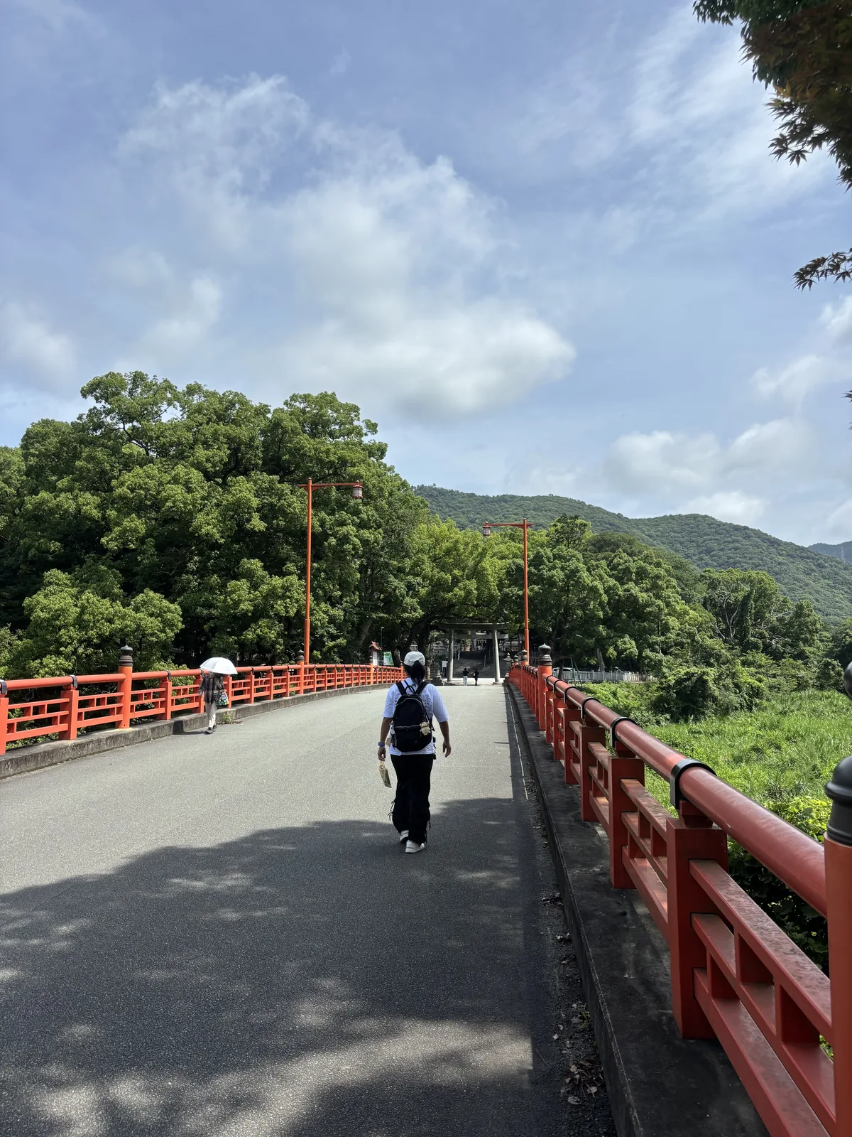 大麻比古神社參道上的橋與前方跨過車道的朱色大鳥居：欄杆是朱塗的，鳥居後方是大麻山的山影