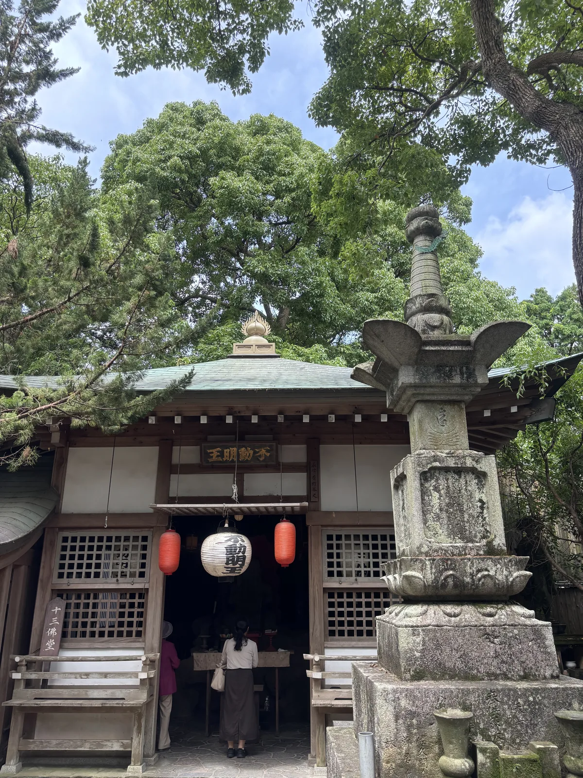 掛「不動明王」扁額的小堂，銅板屋頂已生綠鏽，簷下兩盞紅提燈；堂前立著一具高大的石造多層塔。