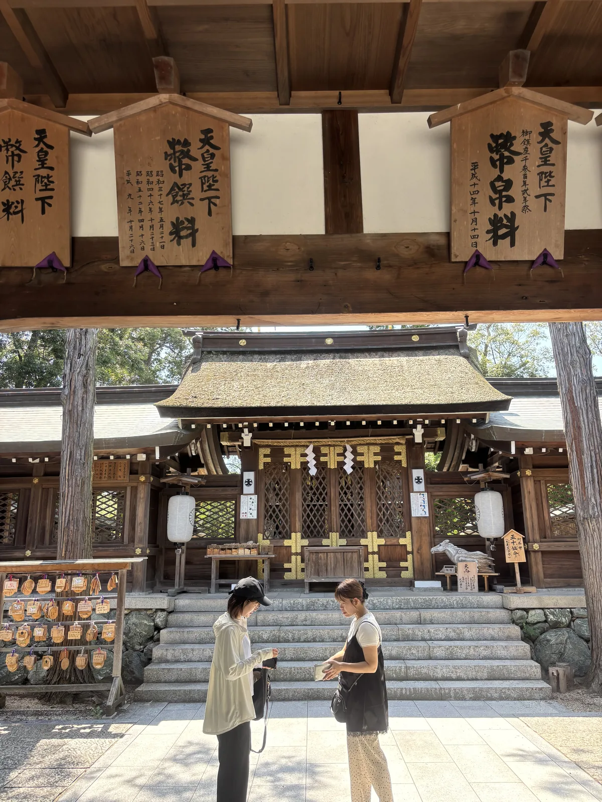 從伊太祈曾神社的割拜殿底下往本殿方向看：頭頂橫樑上一排木札記著歷次的天皇獻幣，正面是中門，右側立著石造神馬