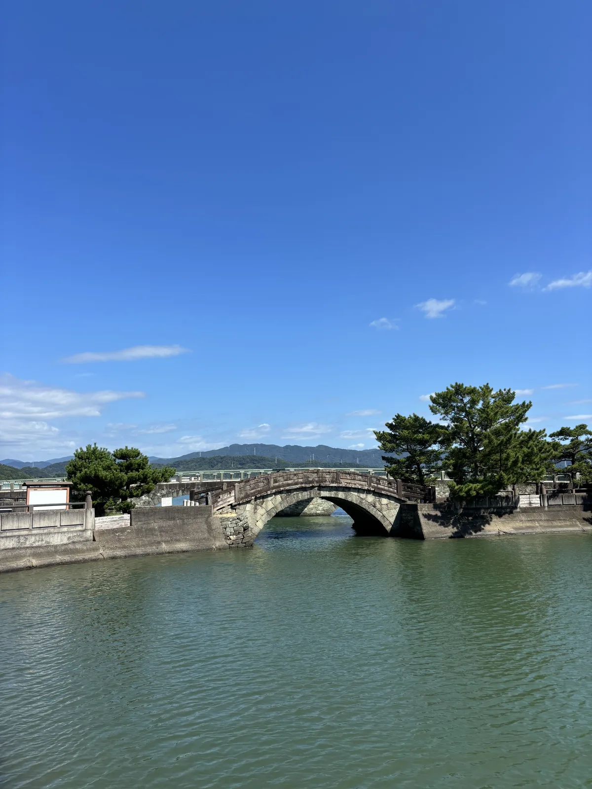 隔水看。綠色的水面、石造的單拱、對岸的松與遠處的名草山。嘉永四年（一八五一）架設。
