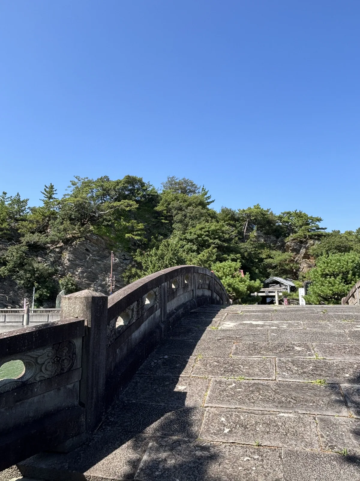 橋面近景。石板鋪的橋面往上拱起，兩側的勾欄上刻著雲形的浮雕——現地板寫那是紀州湯淺的石工石屋忠兵衛做的部分。