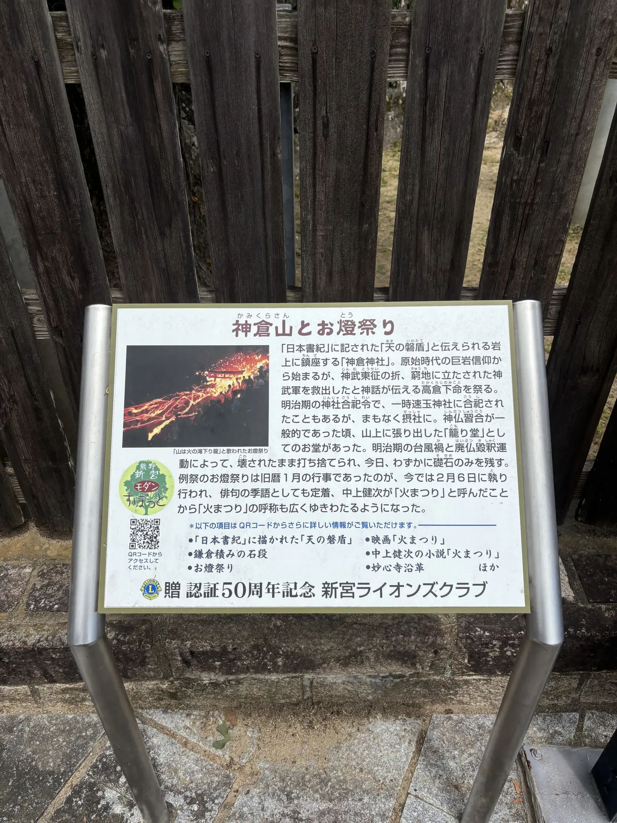 新宮獅子會認證五十週年紀念捐立。板上記著明治的神社合祀令曾讓它一度被合祀進速玉神社、山上「籠り堂」在明治的颱風與廢佛毀釋之後只剩礎石，以及「中上健次が『火まつり』と呼んだことから『火まつり』の呼称も広くゆきわたるようになった」。左側照片是火從石段上流下來的樣子。