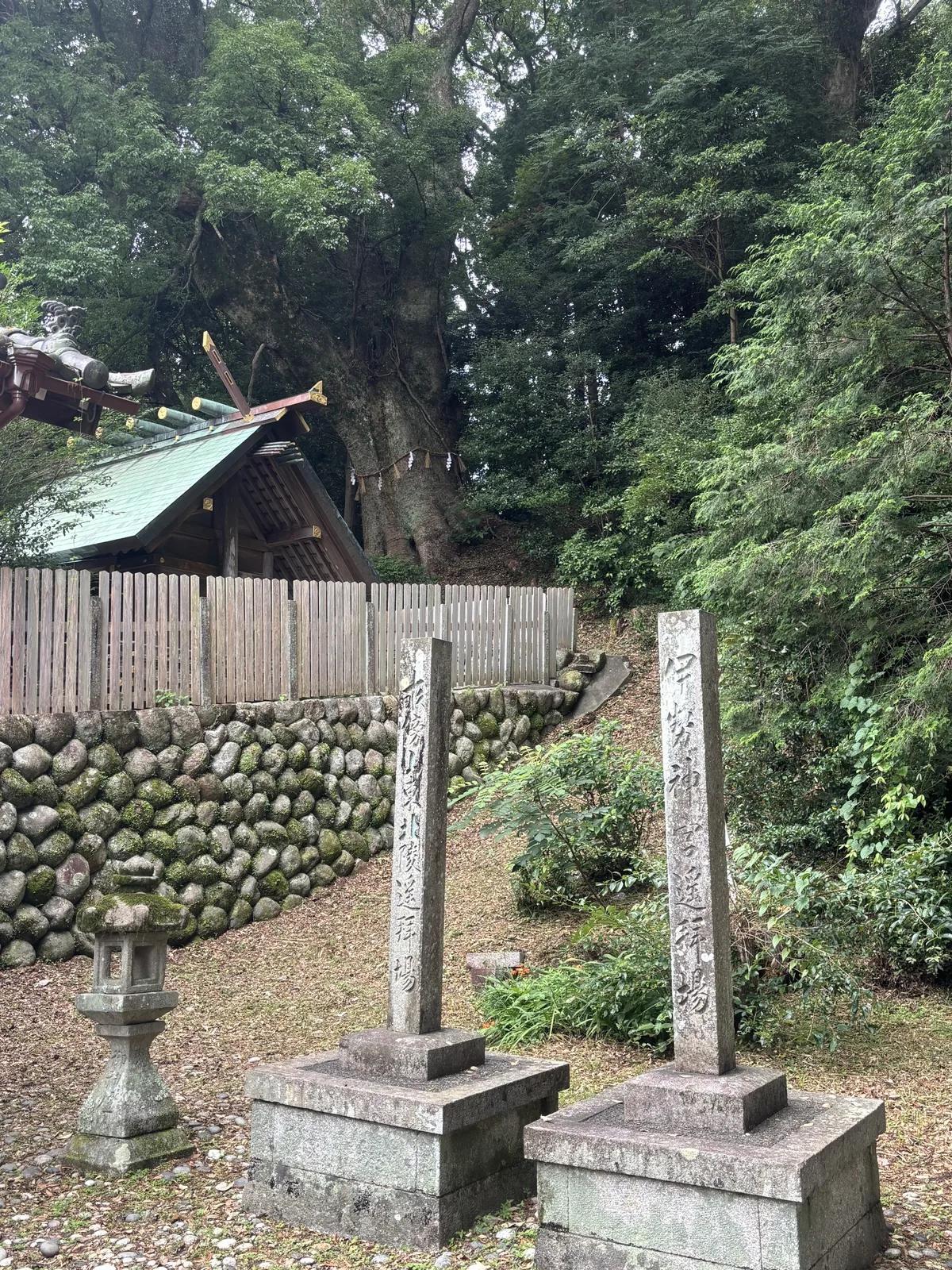 圓石堆砌的石垣上，兩根石柱與一座石燈籠，後方是綠色銅瓦頂的小社——平成九年（一九九七）御遷宮時移過來的舊獅子殿。