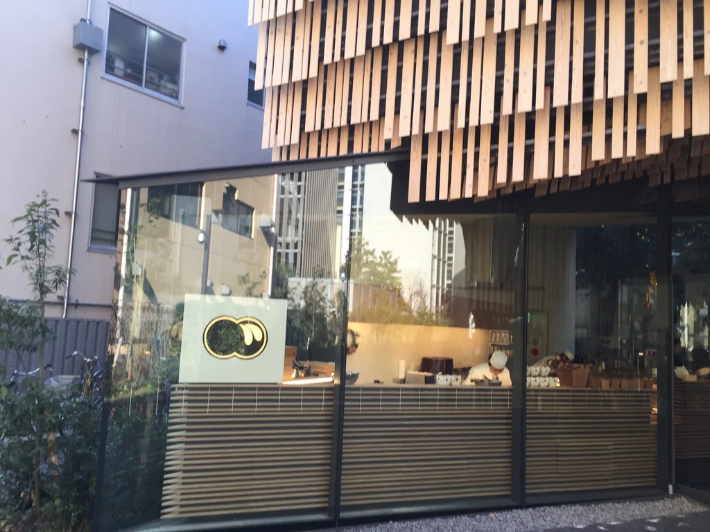 研究館北端，杉板外裝延伸到建築轉角，下方是服務區的玻璃立面與木製的條狀櫃台，櫃台旁立著一塊白色的方形招牌