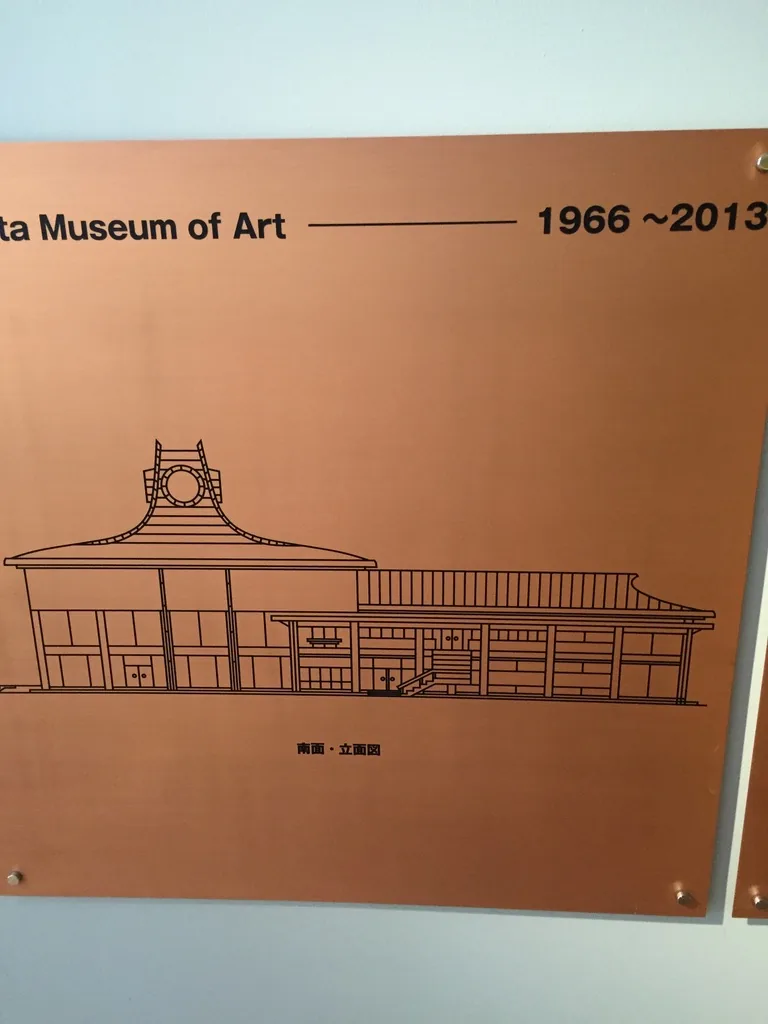 館內的一面銅板，以線描繪出舊美術館的立面，屋頂兩端上揚、中央立著帶圓形裝飾的塔狀頂部，上方標示 1966 至 2013 的年份