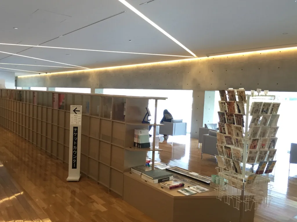 lounge 中的商店區，低矮的書架上陳列書籍與商品，右側是明信片架，後方是面向水庭的玻璃與座位