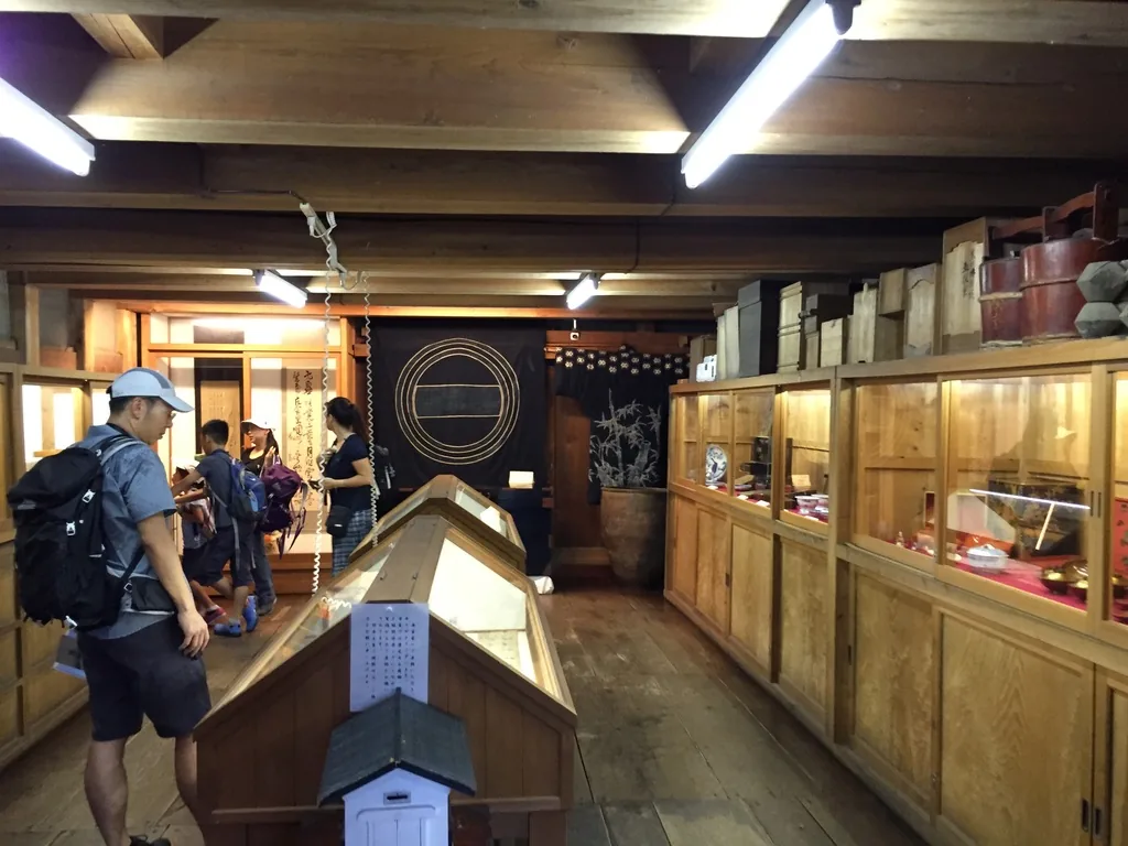 文庫藏一樓的展示空間，兩側沿牆排列木製的玻璃展示櫃，中央是斜面的展示台，天花露出木梁並裝設日光燈，後方懸掛著紋章的布幕