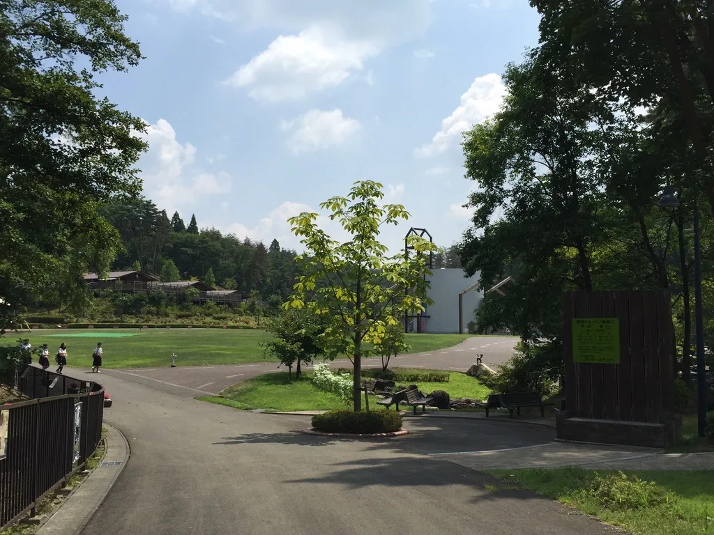 自廣場北望：步道通往一片草坪，遠處林緣可見賢治之學校的白色量體