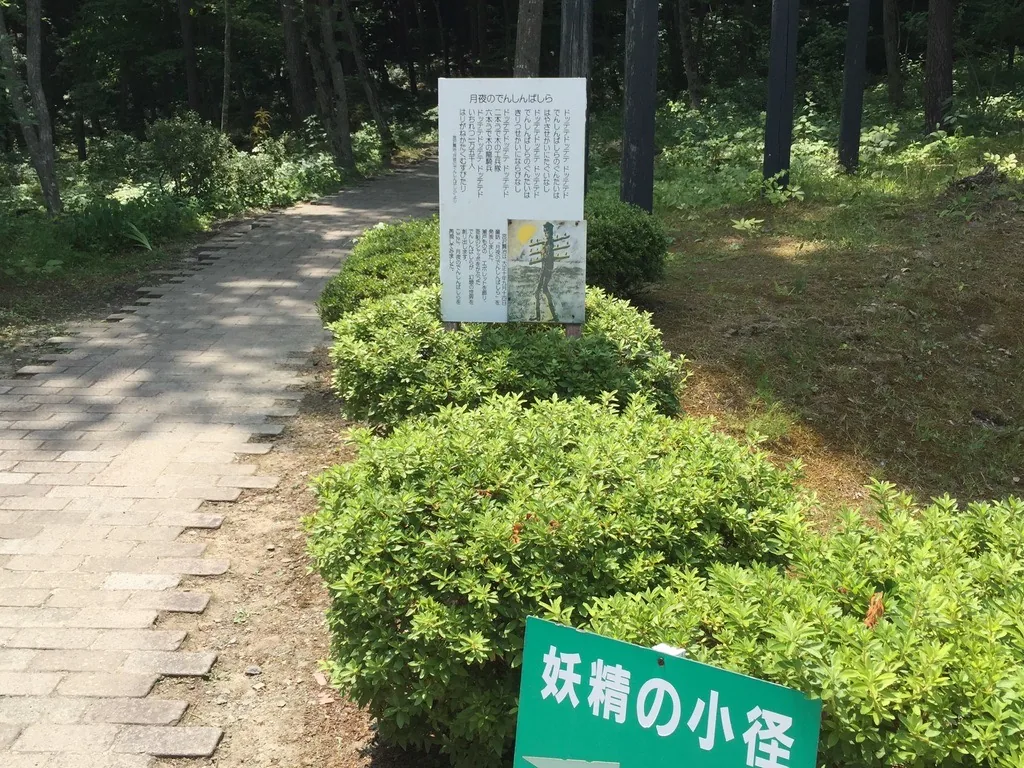 妖精小徑：灰色石磚鋪成的步道，一側是灌木，路旁立著白色的解說板