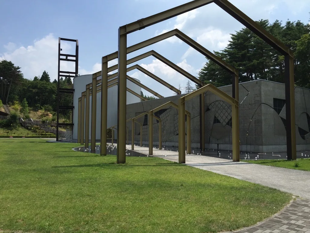 金色家形框列自草坪側展開，框沿混凝土牆逐一縮小，框下為黑色地坪
