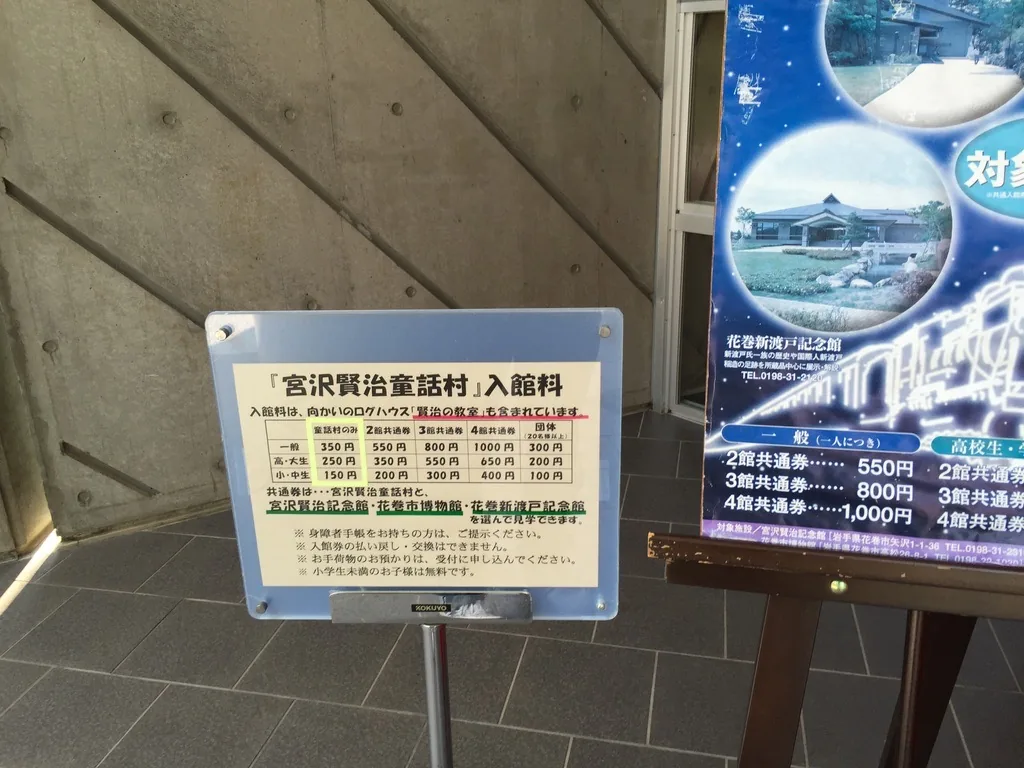 入口處的混凝土牆，表面留有斜向的模板接縫，前方立著入館料的告示牌
