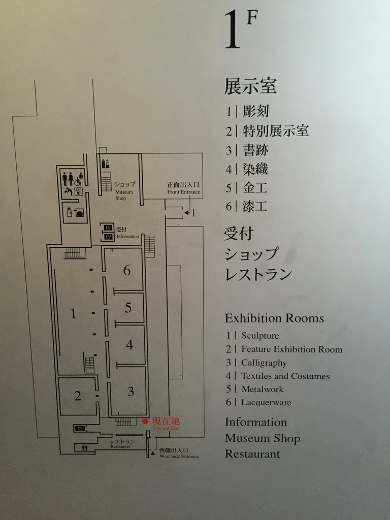 平成知新館一樓的樓層導覽板，左側是一樓的平面圖，標示著六間展示室與受付、商店、餐廳的位置，右側以日文與英文列出展示室名稱與設施名稱
