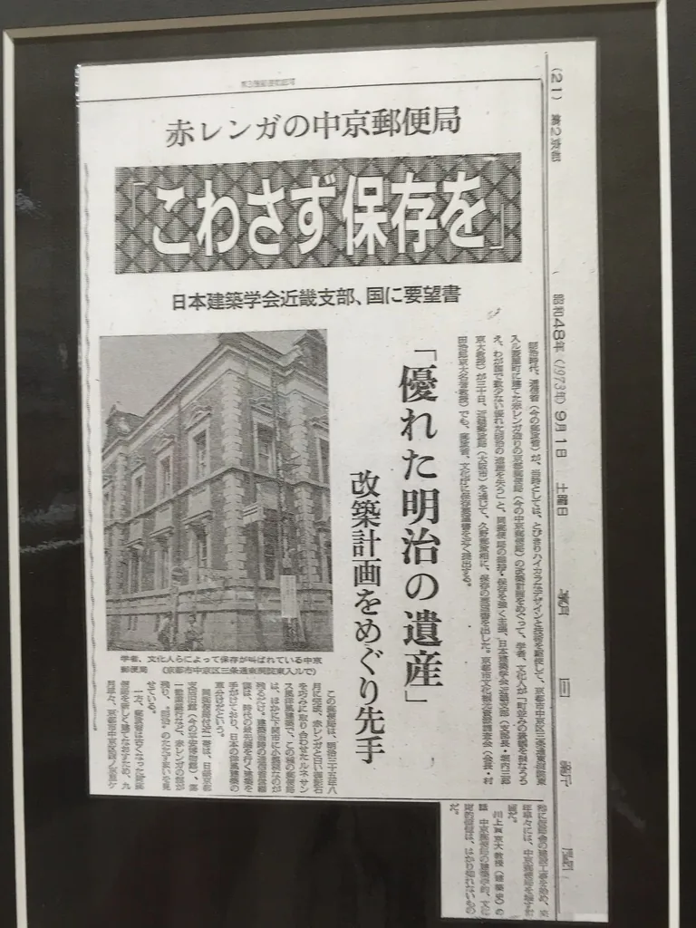 一則裱框的報紙剪報，大標題寫著「不要拆，保存它」，副標是「日本建築學會近畿支部向國家提出要望書」與「優秀的明治遺產」，左下方是一張紅磚建築轉角的黑白照片，旁邊是直排的報導內文