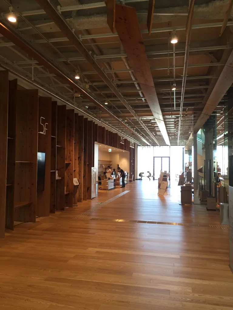 五樓的走廊，左側是一整面以杉木板組成的展示櫃與牆，右側是一排直立的杉木柱，天花是外露的鋼骨與杉木條，走廊盡頭是一扇明亮的窗與一處服務台