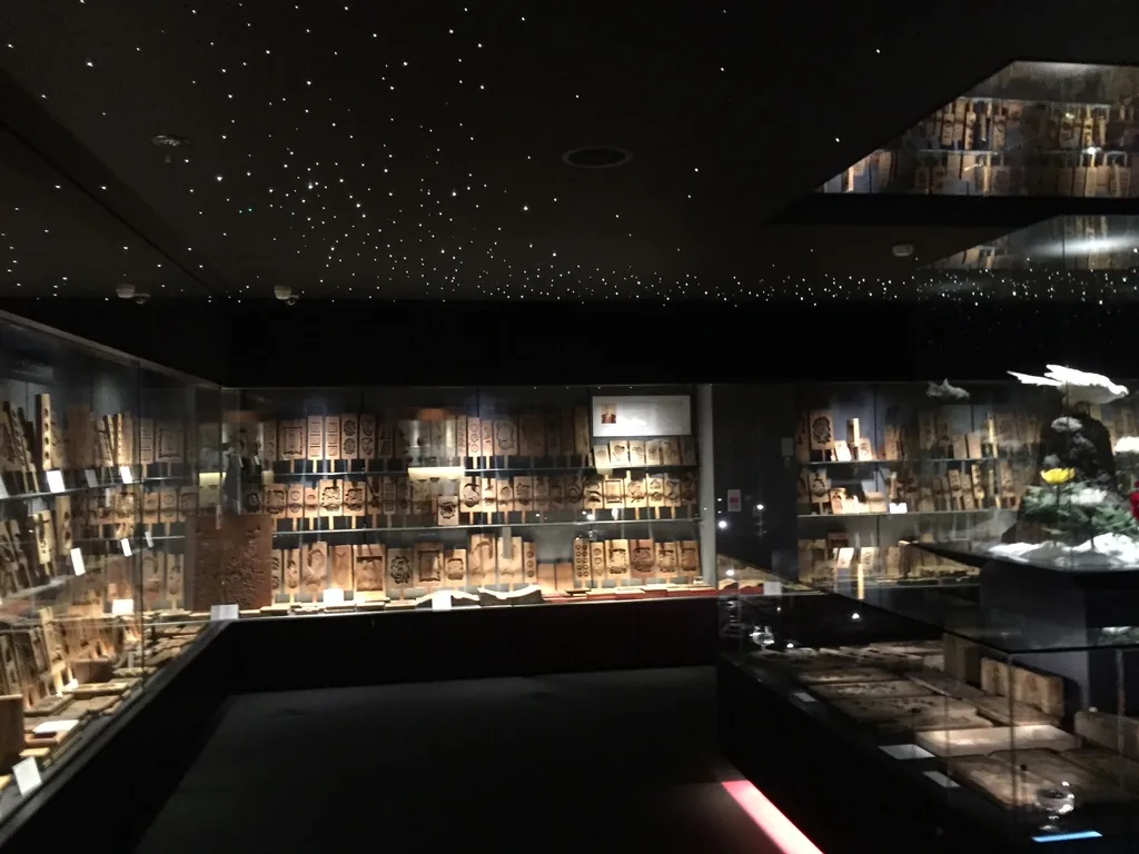 展示室的另一個方向，左右兩側與正面的牆面排滿木型，前方是低矮的展示台，天花上的光點與一處向上凹入的方形開口