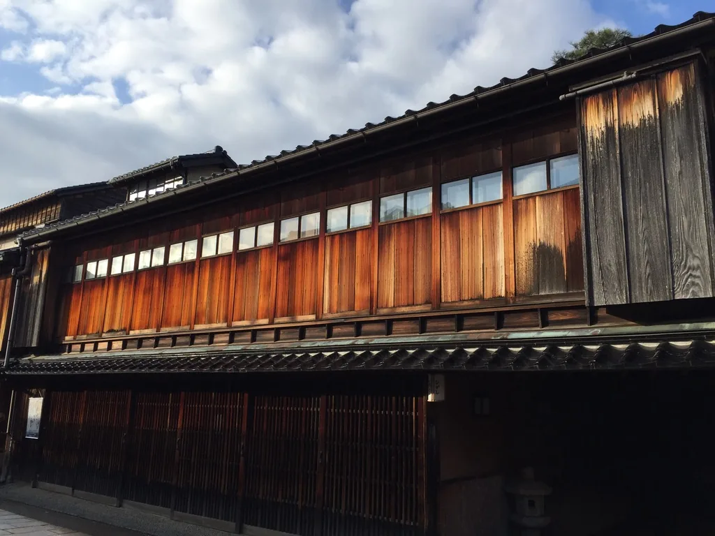 東茶屋街的一棟二層茶屋建築，二樓是一整排木框開口與外露的木柱，一樓為深色木格子，屋頂為黑色瓦葺