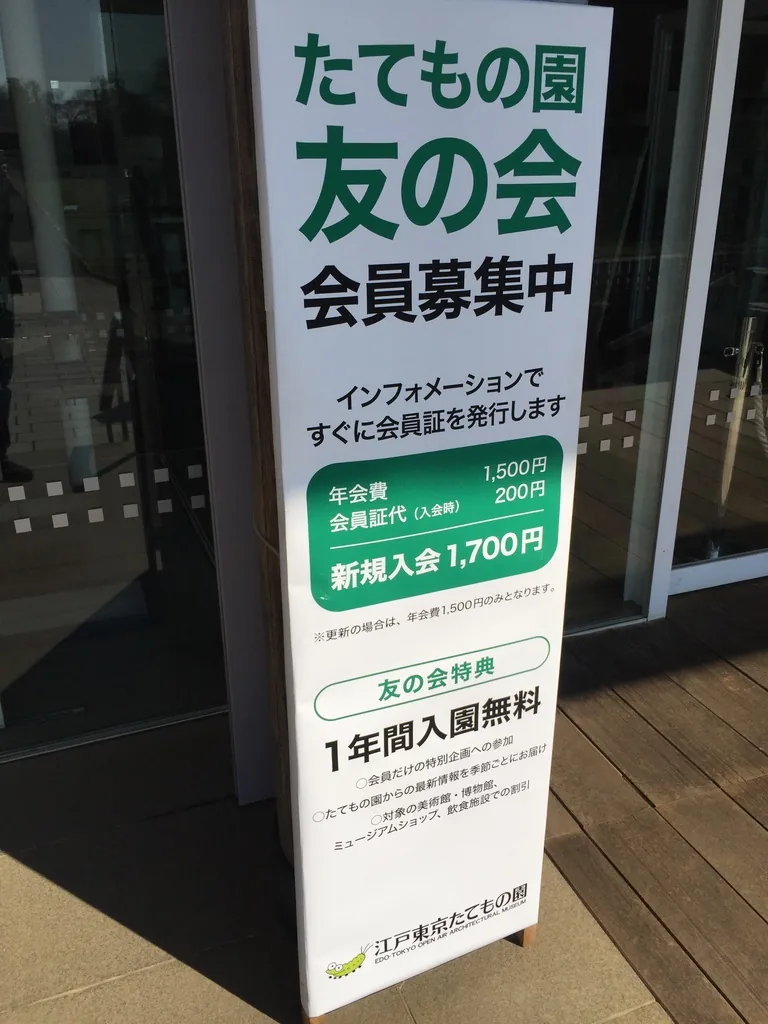 遊客中心入口旁的立牌，綠底白字寫著建築園友之會的招募，下方列出年會費與入會的優惠，立牌後方是玻璃門