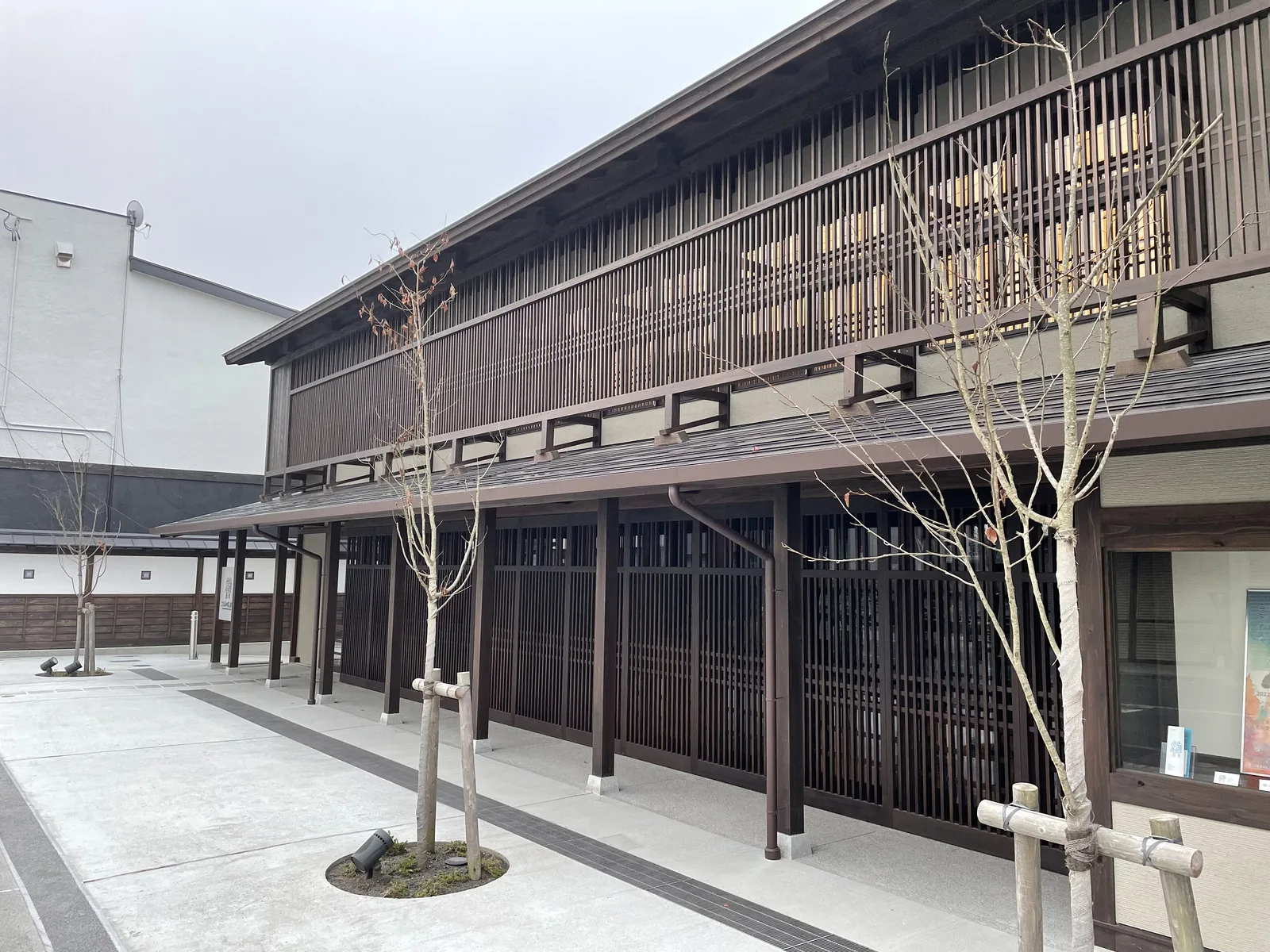 清晨霧中的沿街立面：木格子、二樓出挑與深簷