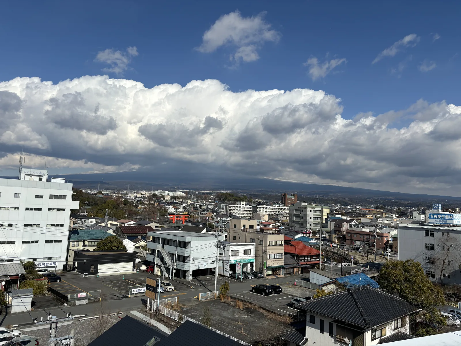 自露台向北看，前景是富士宮的市街與低層建築，遠方的山被大片的積雲遮住，只露出山麓的緩坡