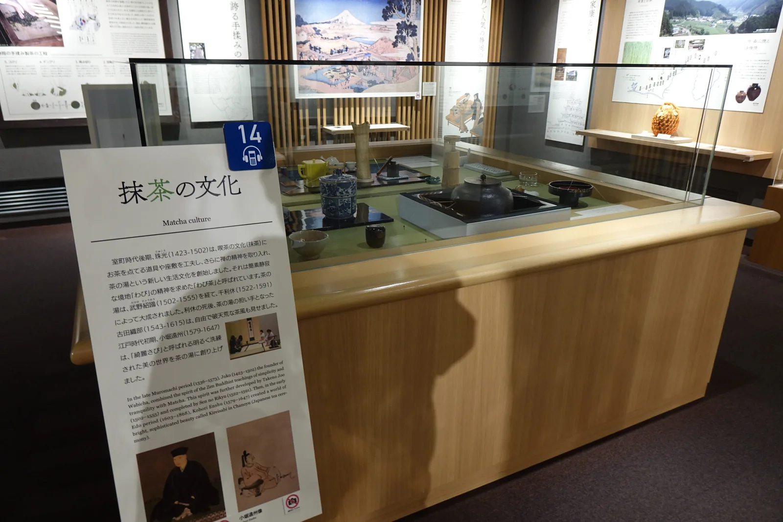淺色木製的展示台，台面鋪榻榻米並圍以玻璃，中央是爐與鐵釜，四周擺著茶道具，前方立著抹茶文化的解說板