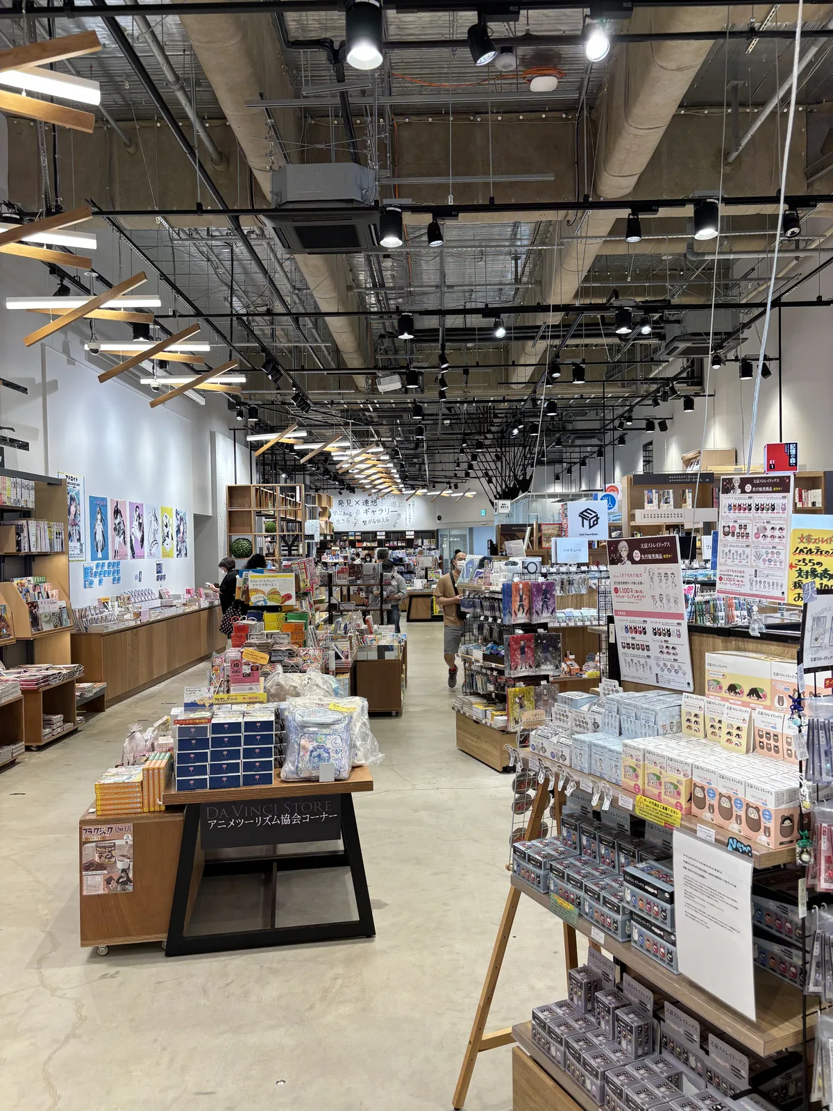 本棟二樓的書店 Da Vinci Store，高大的空間中排列著木製的書架與平台，天花是外露的設備管線與軌道燈，店內有幾位顧客
