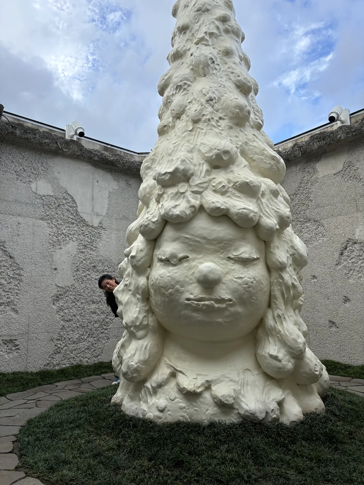 八角堂內部，八角形灰白色粗面牆體圍合、頂部開放見天，中央矗立白色量體雕塑，基座為石板鋪面與草皮