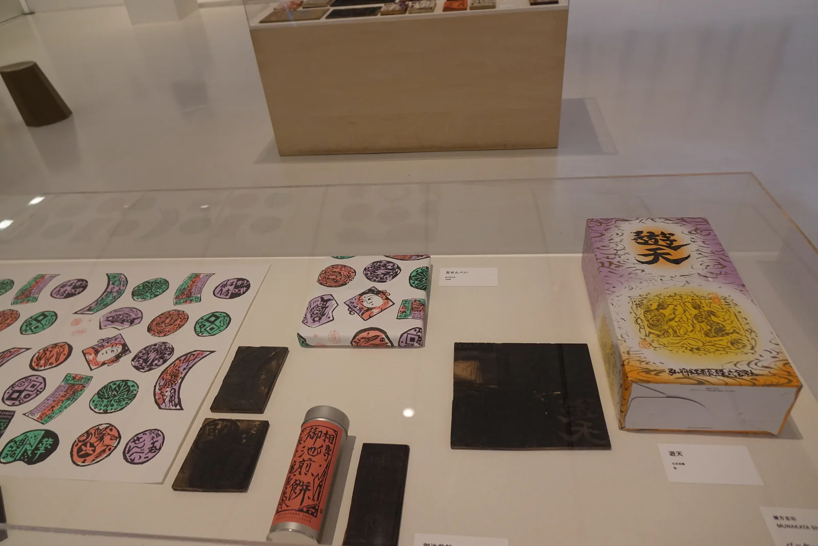 商店玻璃展示櫃，陳列棟方志功主題紀念商品，含彩色印花糖果、印章造型擺飾與印有其名的禮盒