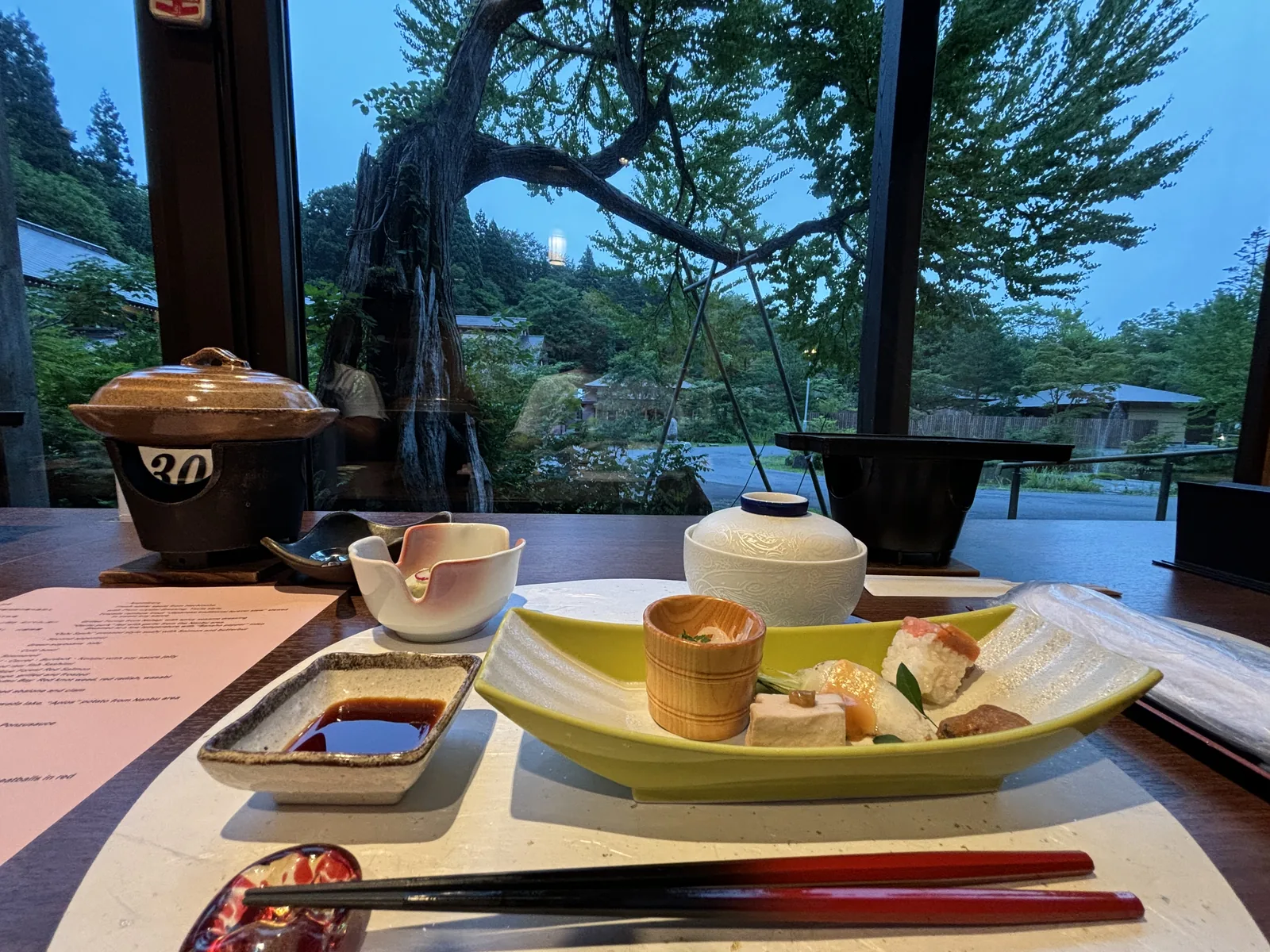 晚餐座位面向落地玻璃，窗外是一株枝幹粗壯的老樹