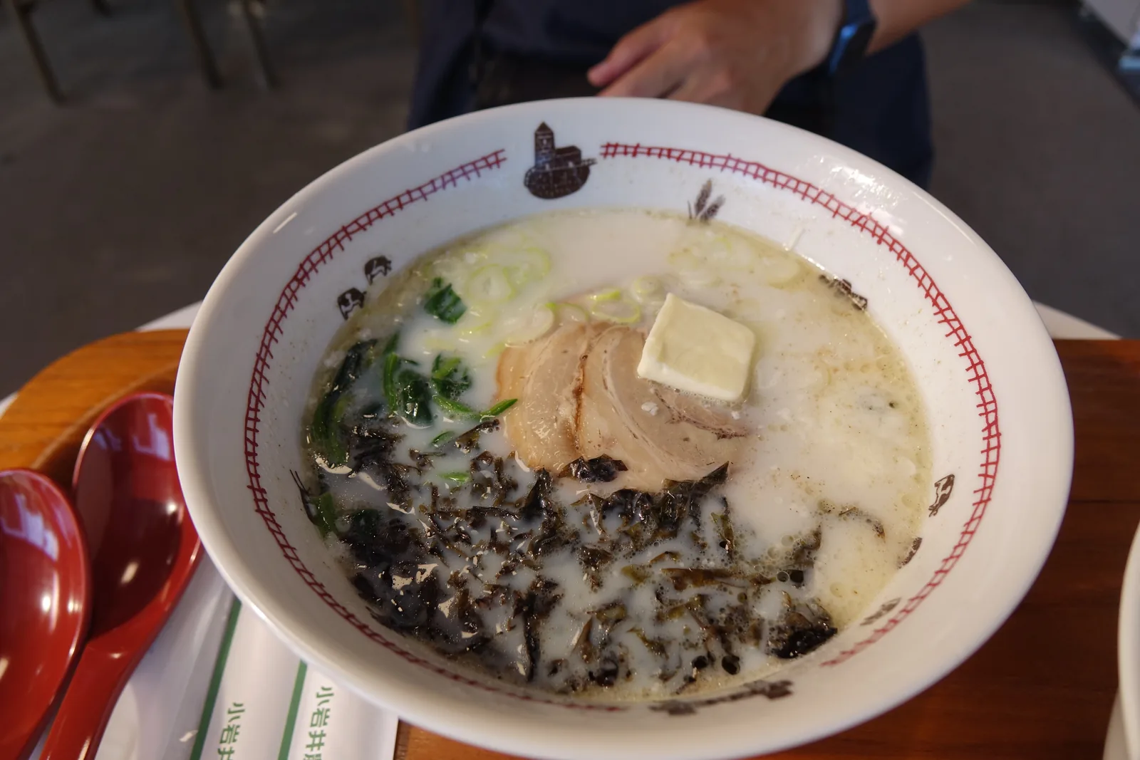 乳白色湯頭的牛奶拉麵，上面放著一方奶油、叉燒與海苔