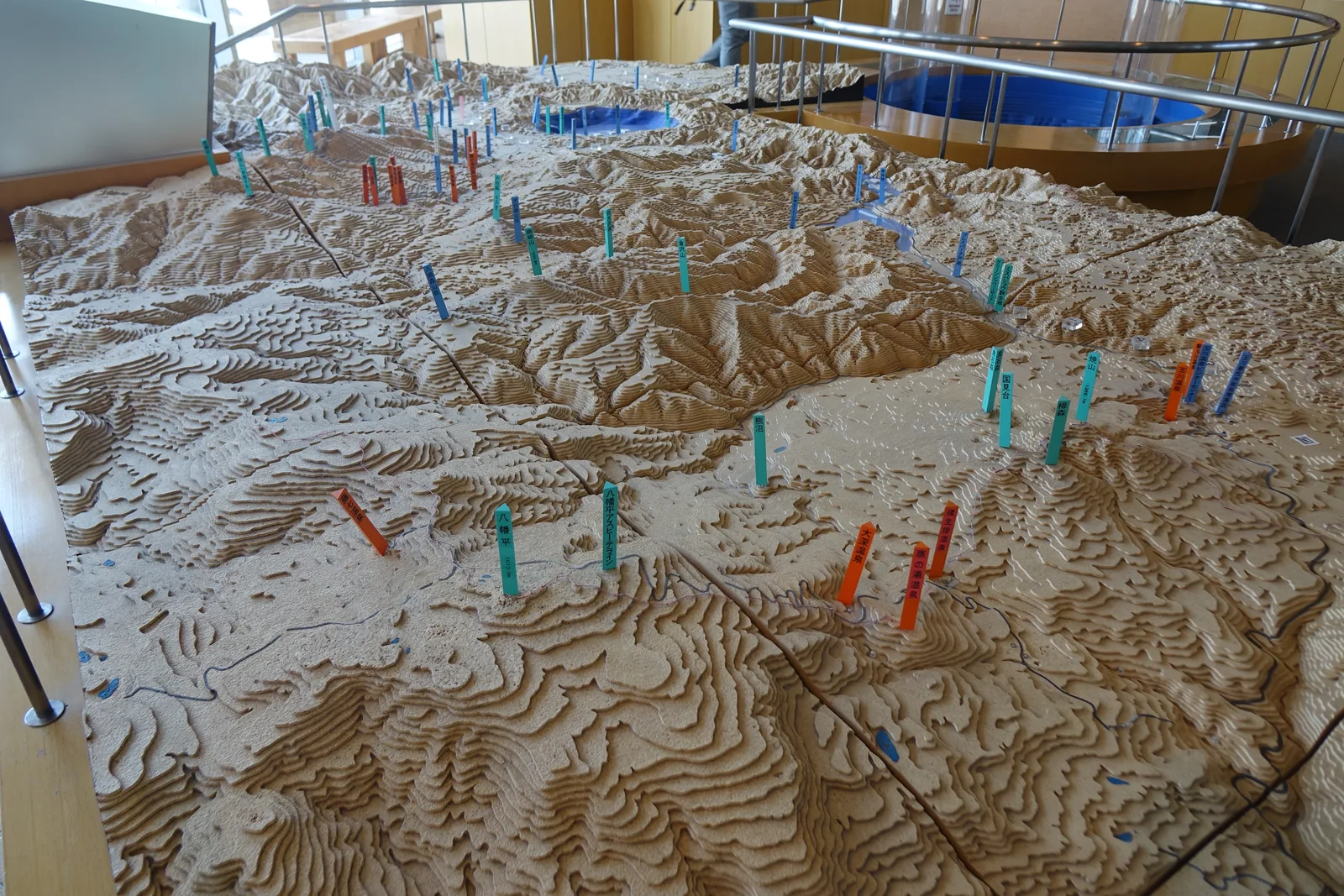 森與遺跡展示室的立體地形模型：等高線疊成的山地上，插滿標示遺跡位置的彩色標籤