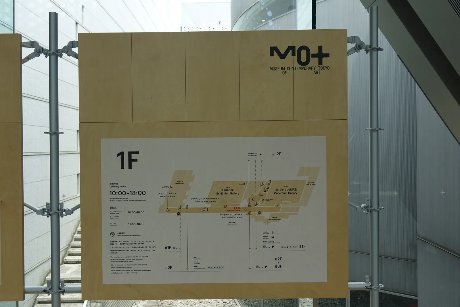 一樓的標示家具，淺色木夾板面板以金屬管柱固定，上方印有美術館標誌，下方為一樓平面圖與開館時間