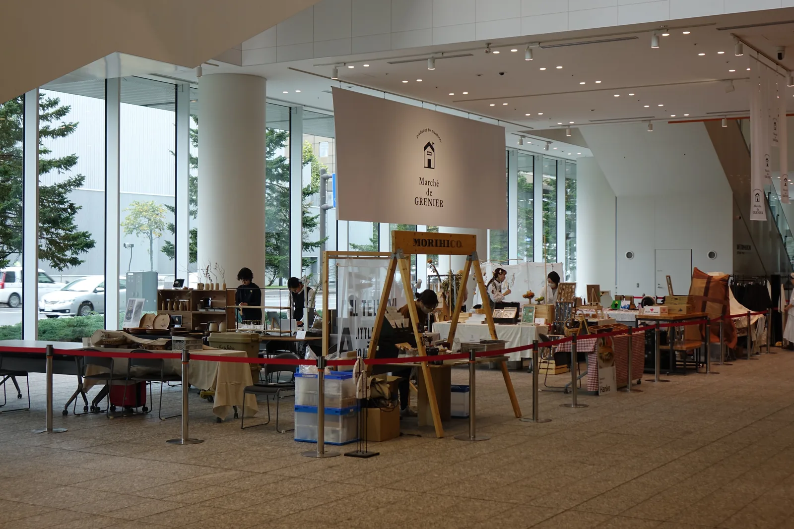 一樓 SCARTS mall 的市集活動，攤位以紅色圍欄區隔，上方懸掛市集布旗，後方為玻璃帷幕與戶外植栽