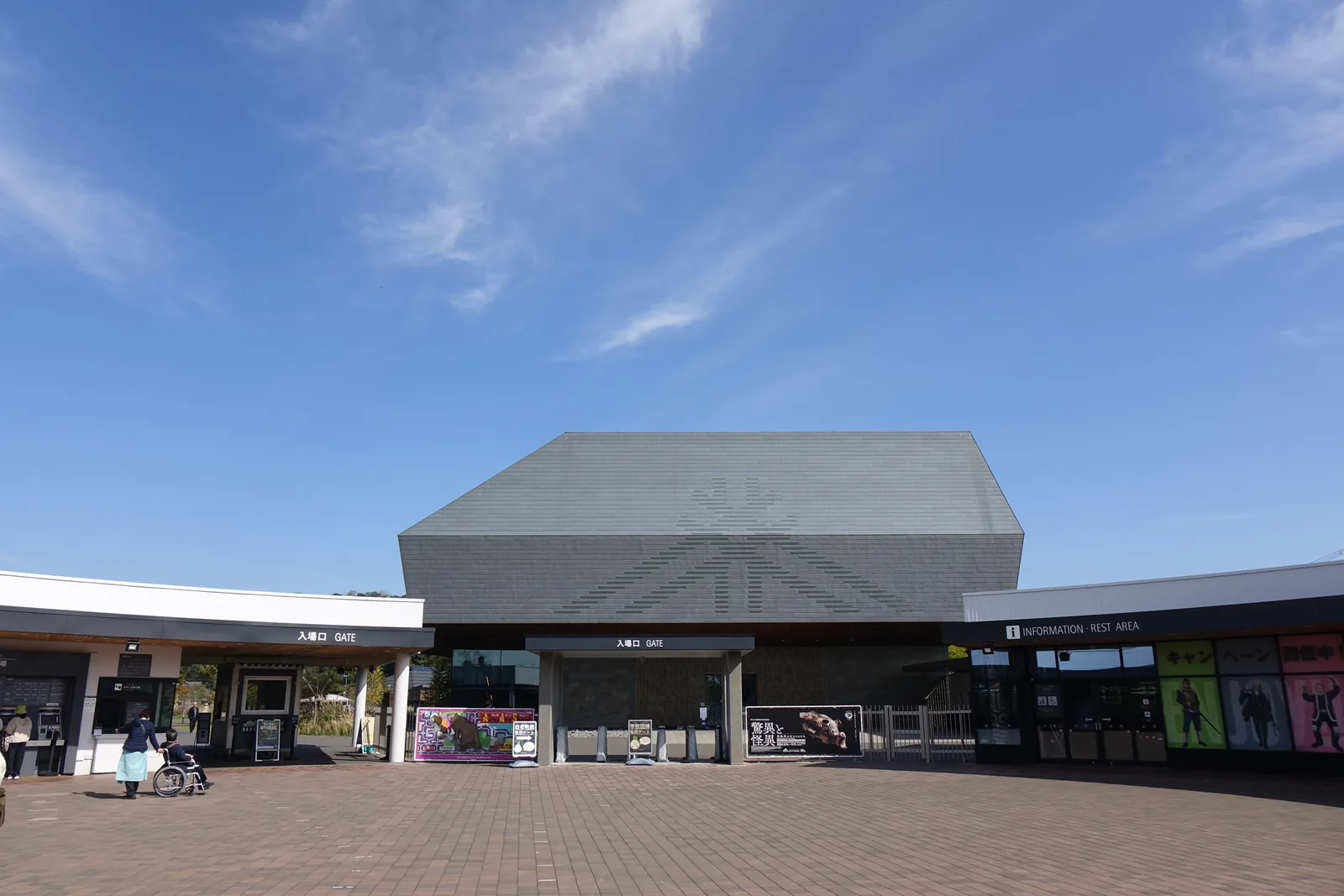 入口棟正面的入場閘門，兩側為一層的入口棟，其後為博物館西端的灰色量體，前方為磚鋪廣場