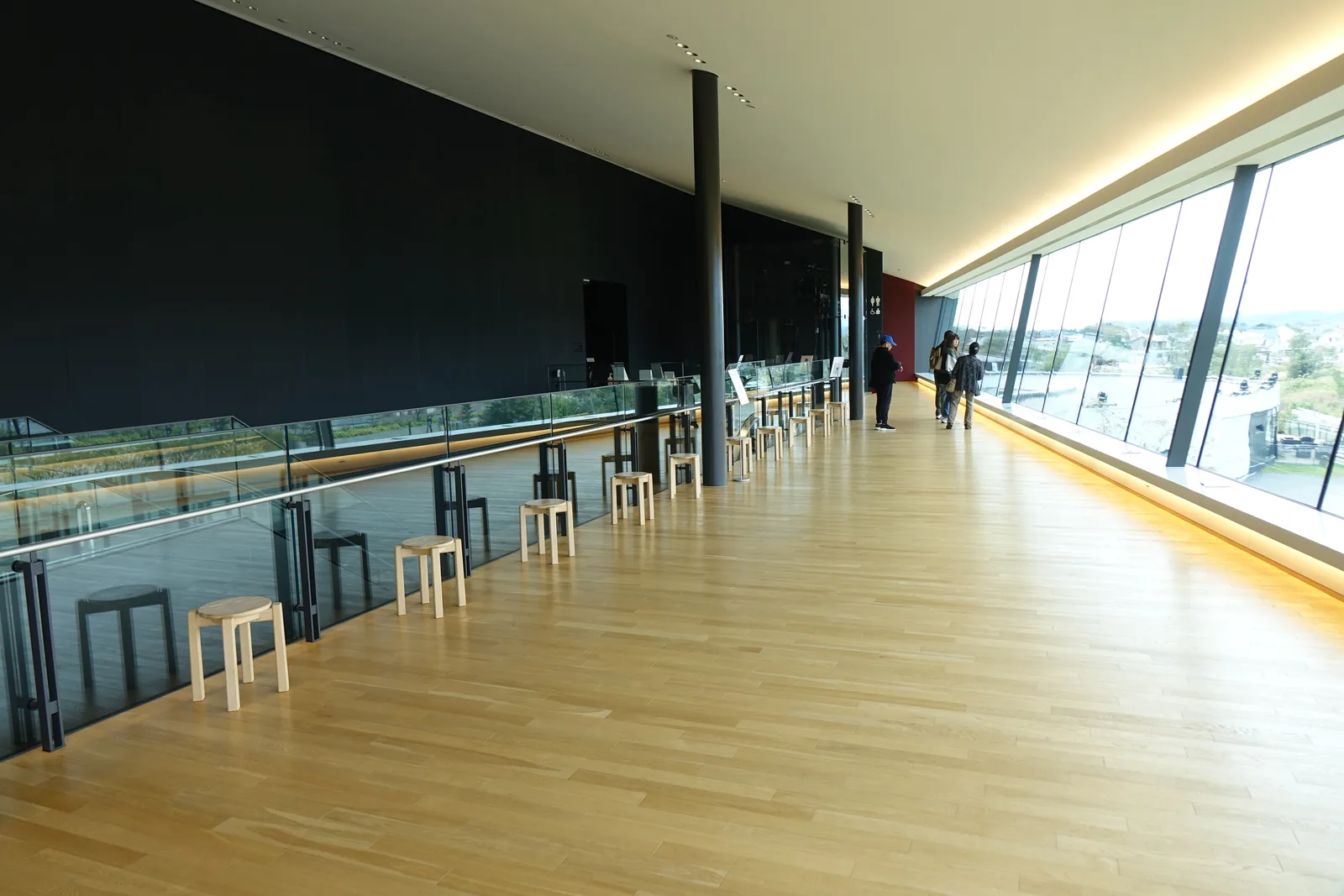 自 Panoramic Lobby 俯看園區，下方為草地與水池，左側為體驗交流 hall 銀色的曲面屋頂，遠方為丘陵