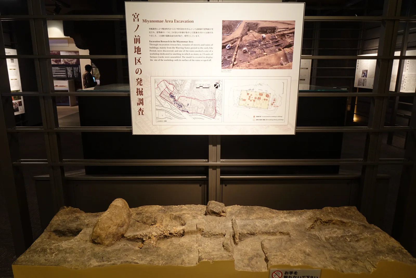 第三展示室，深色鋼製格架構成的牆面上固定著解說板，下方是一塊以剝取方式取得的遺構地面，平放在展示台上
