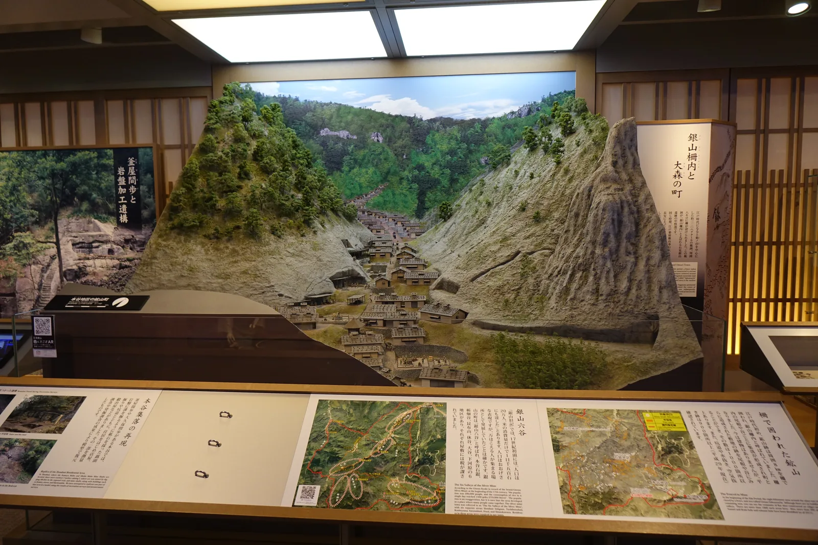 展示室中的大森町並模型，兩側是陡峭的山坡，谷底沿著河川排列著瓦頂的町家，前方的展示台上是空中照片與解說
