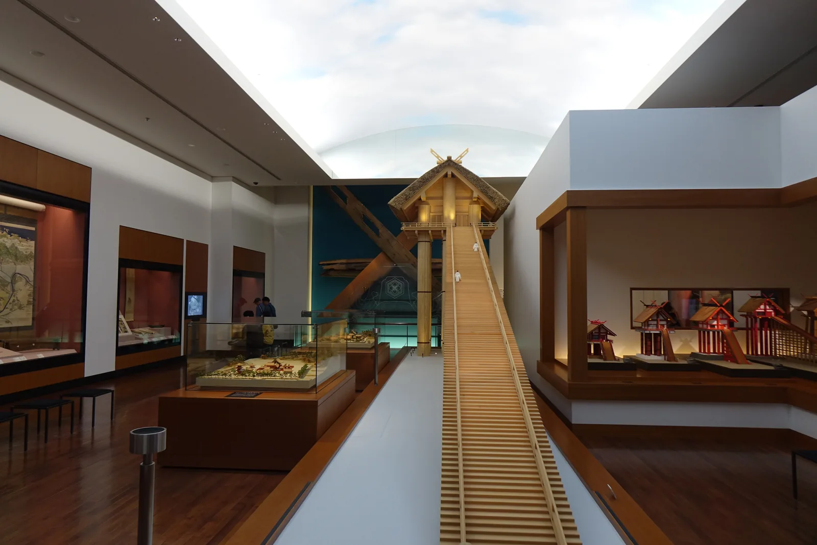 展示室中央的大型社殿模型，社殿立在長柱之上，一道長階梯自地面斜向升到社殿，上方的天花板開成明亮的弧形面，兩側是展示櫃與牆面上的小型社殿模型