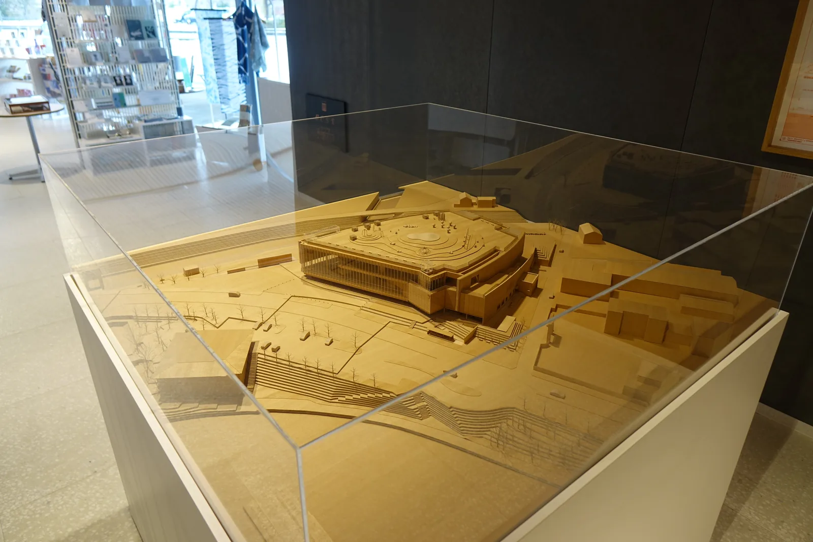 館內展示的建築模型，以淺色木材製成，呈現美術館的量體、屋頂與周邊的道路和運河，放在玻璃罩內