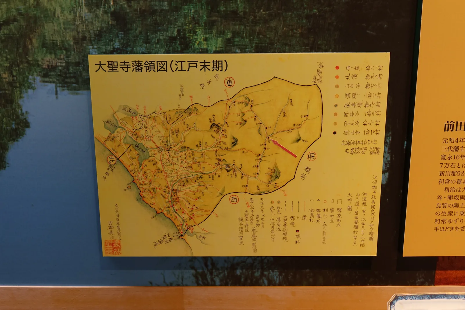 展示室中的一幅古地圖，以黃色為底，描繪大聖寺藩的領地範圍與村落，地圖右側列著圖例，地圖鑲在深色的框內，旁邊是一段說明文字