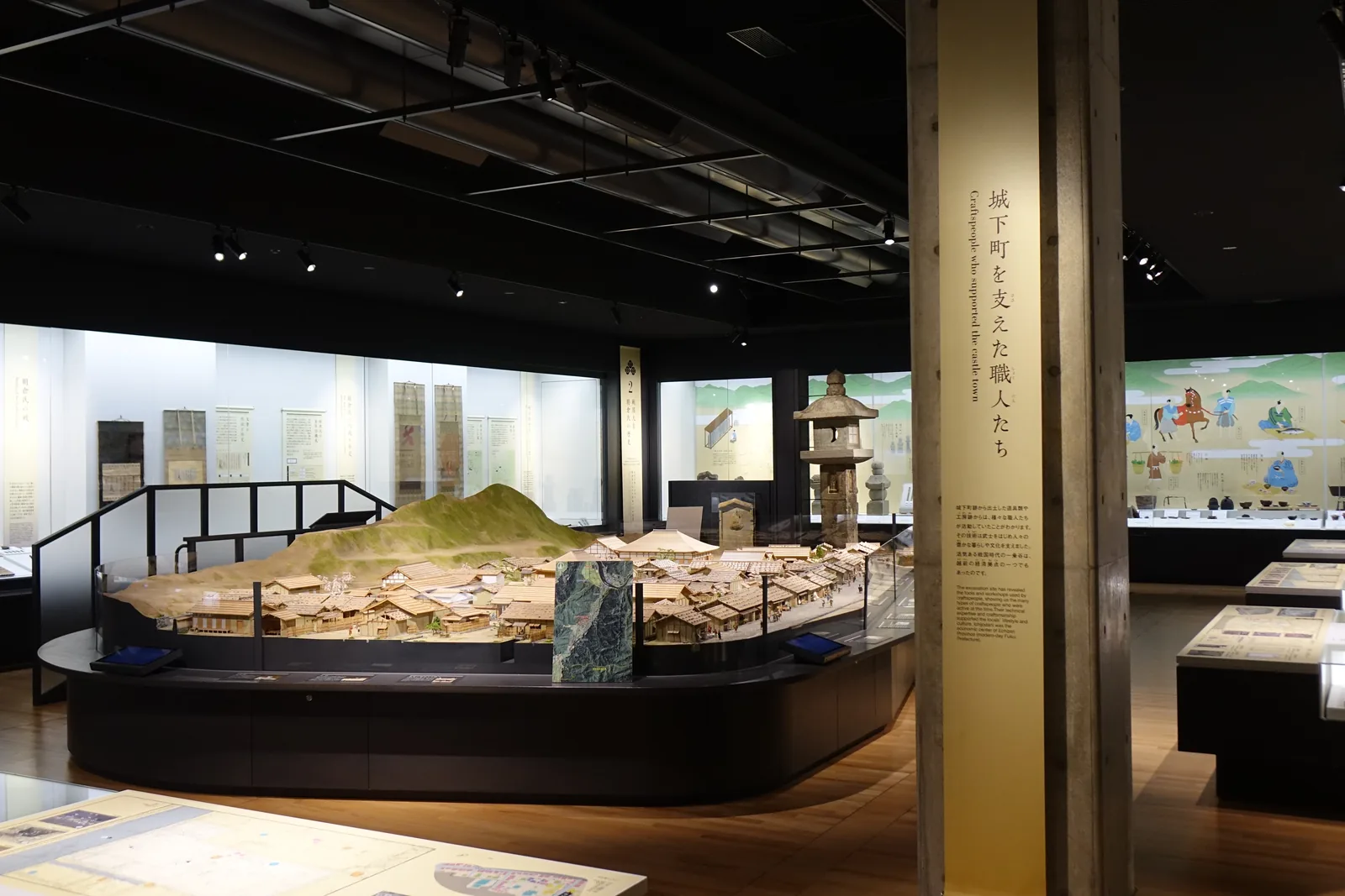 二樓的基本展示室，中央是一座一乘谷的地形模型，模型旁立著一座石塔，四周是成排的玻璃展示櫃，天花是深色的，牆上掛著數幅長條的說明布幕
