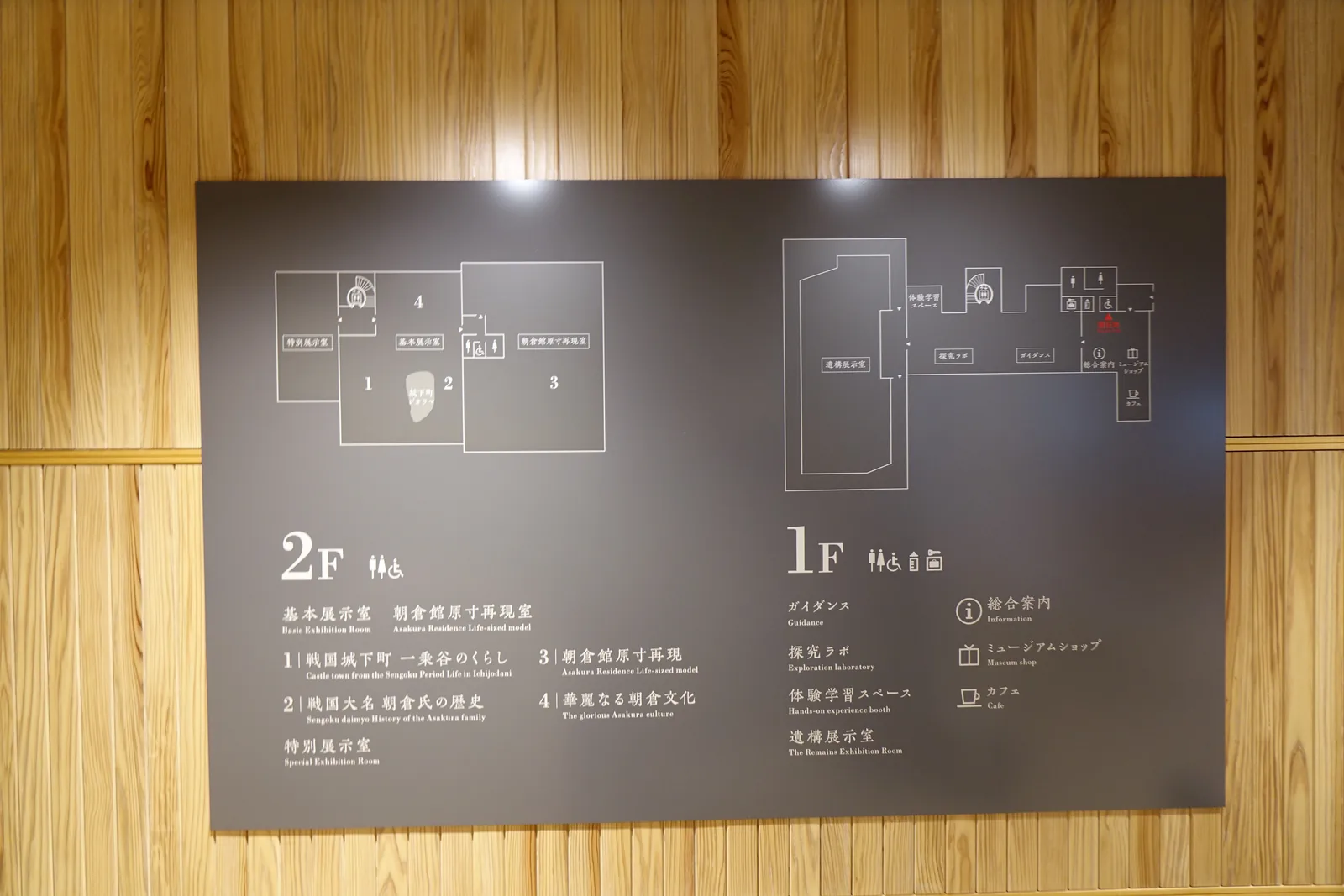 一樓牆上的樓層案內圖，深灰色的板上以白線畫出一樓與二樓的平面與各室的名稱，板的周圍是直拼的杉木板牆與杉木板天花